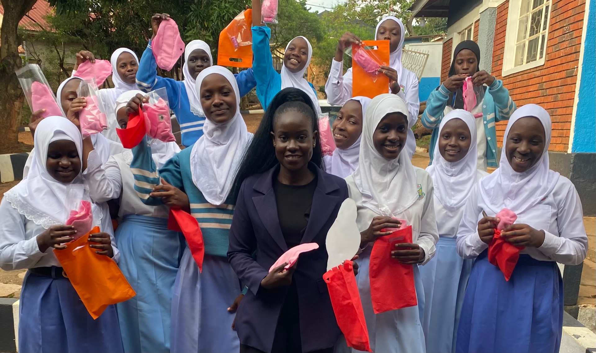 Nassuuna Grassroots Education Initiative with Ugandan schoolgirls holding reusable sanitary pads