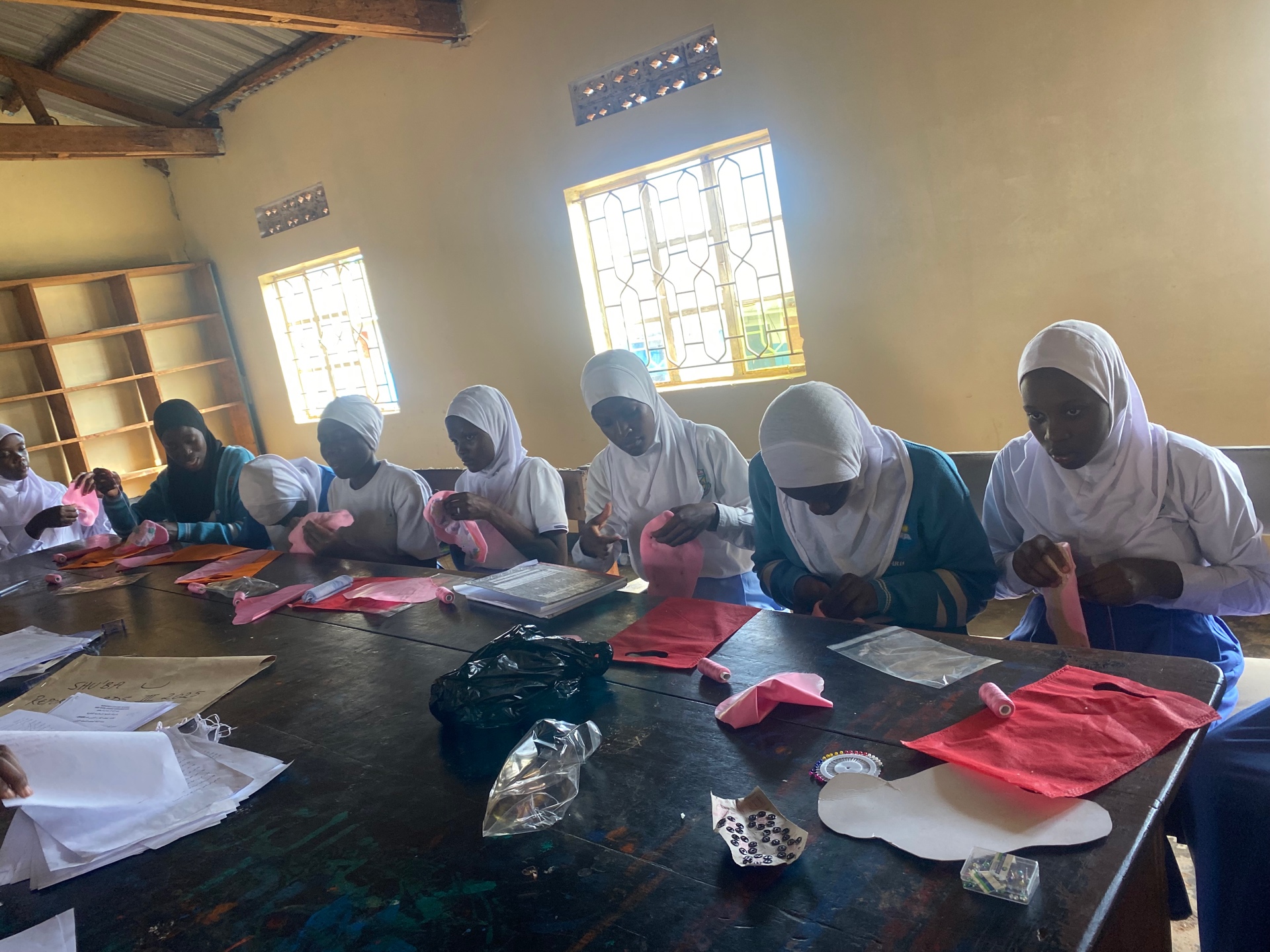Girls sewing reusable pads with pink threads and locally sourced materials